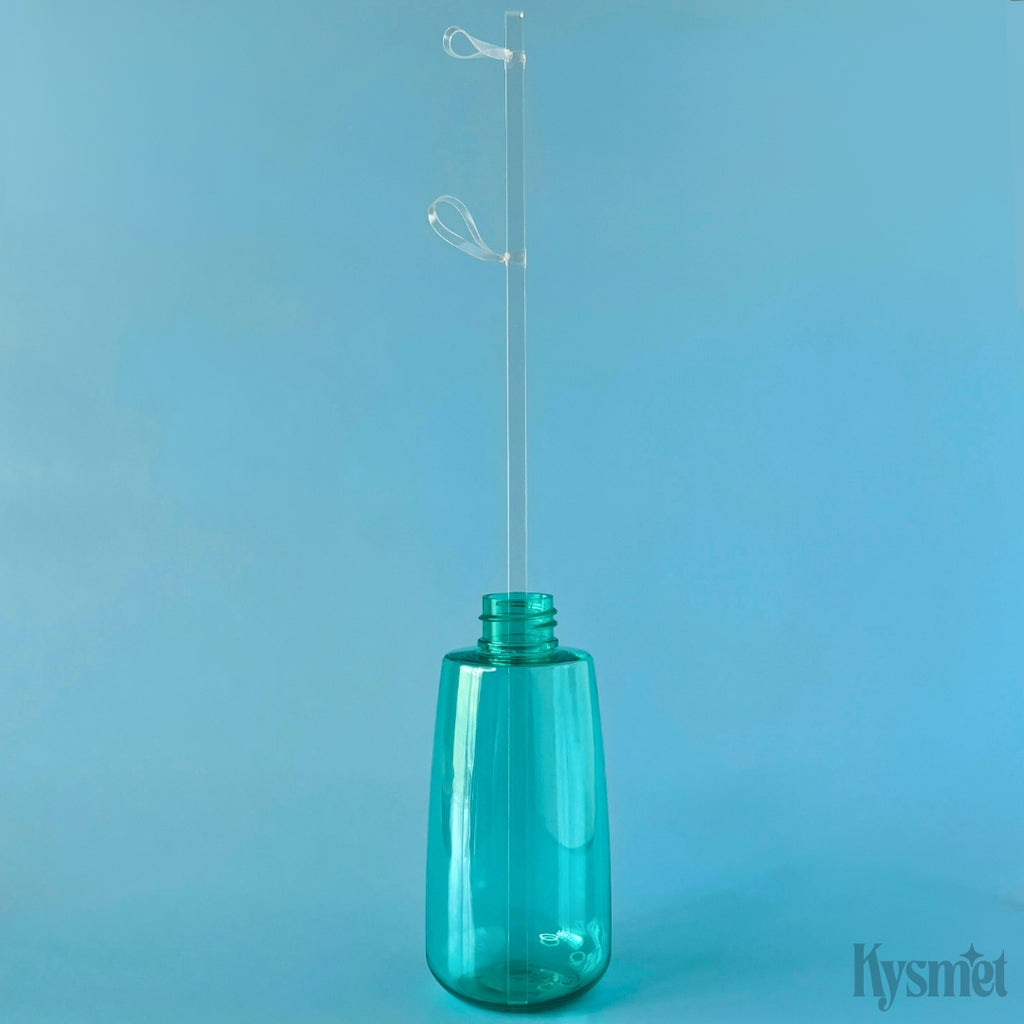 A teal bottle holds a clear plastic stick with two clear rubberbands at the top, against a blue background.