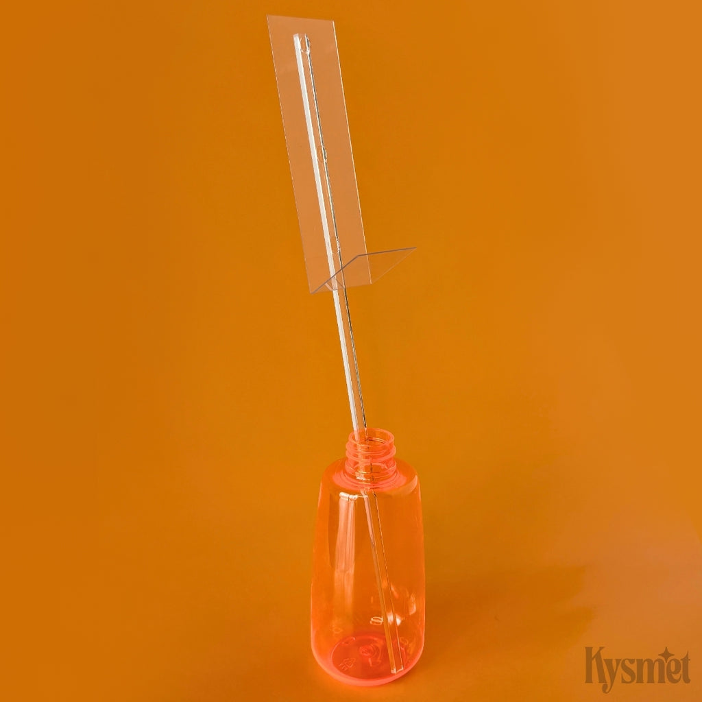 An orange bottle holds a clear plastic stick with a rectangle piece of acetate, against an orange background.