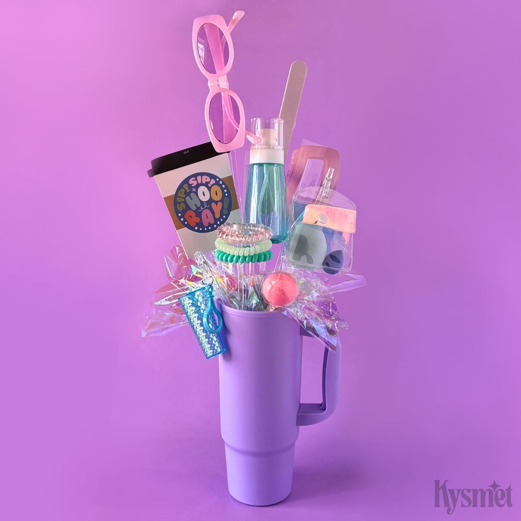 Purple tumbler filled with various items including a gift card, candy, and cosmetics on a purple background.