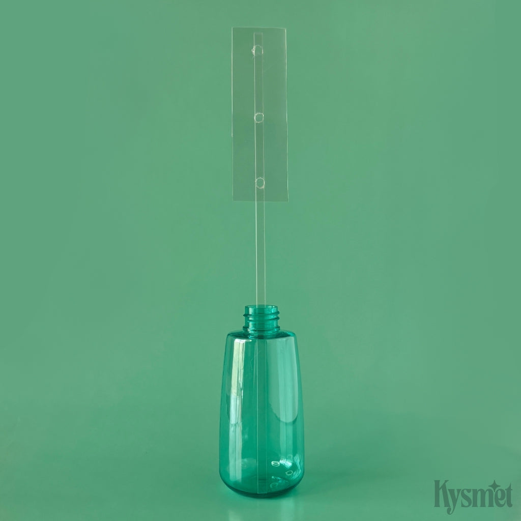 A teal bottle holds a plastic stick with a rectangle piece of acetate of the top, against a teal background.